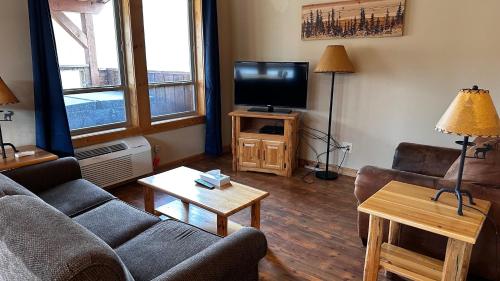 a living room with a couch and a television at Methow River Lodge and Cabins in Winthrop