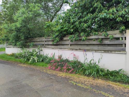 a white retaining wall with plants on the side of a road at L'ENVOLEE in Champdeniers-Saint-Denis