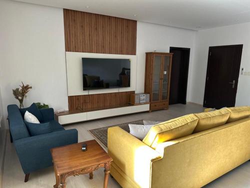 - un salon avec un canapé jaune et deux fauteuils bleus dans l'établissement Azzam's Apartments, à Médine