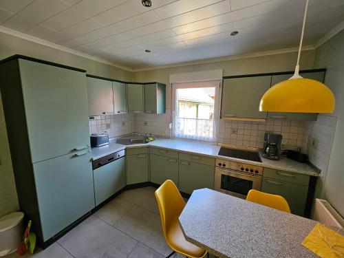 a kitchen with green cabinets and a table with yellow chairs at Ferienwohnung Hanni in Gräfenhainichen