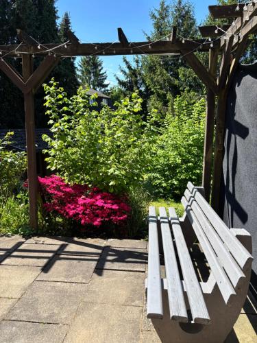 a white bench sitting next to a garden with pink flowers at Ferienwohnung LeJaju in Friedrichsthal