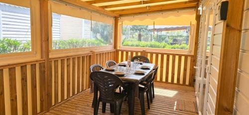 une salle à manger avec une table et des chaises sur un porche dans l'établissement MOBIL HOME CAMPING LES SABLES DU MIDI 3 chambres, à Sérignan
