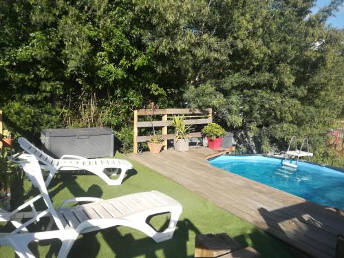 une cour arrière avec une piscine et une terrasse avec deux chaises dans l'établissement Jolie rez de villa avec piscine à 16km d ajaccio, à Peri