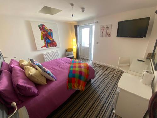 a bedroom with a purple bed and a flat screen tv at Sanctuary Rooms in Brightlingsea