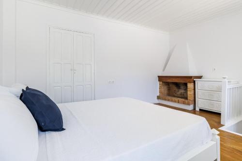 a white bedroom with a white bed and a fireplace at Villa Skopelita in Skopelos Town