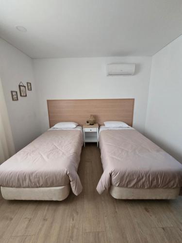 2 Betten in einem Zimmer mit weißen Wänden und Holzböden in der Unterkunft Vivenda Branca Martinho II in Peso da Régua