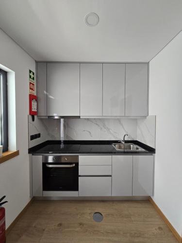 a kitchen with white cabinets and a sink at Vivenda Branca Martinho II in Peso da Régua
