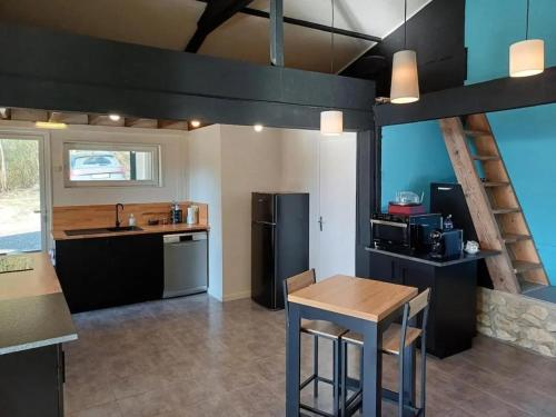 Il comprend une cuisine équipée d'une table et d'un réfrigérateur noir. dans l'établissement Chalet avec bain à remous à Saint-Loup-Terrier, à Saint-Loup-Terrier