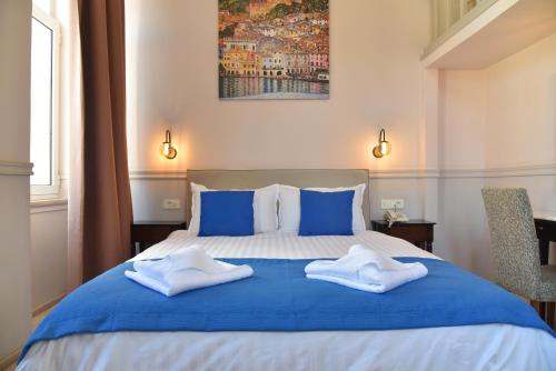 a bedroom with a blue and white bed with two towels at Pension 2Be in Nafplio