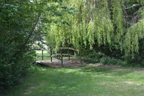 a wooden bridge in a field with trees and grass at The Chiltern Lodges at Upper Farm Henton in Chinnor