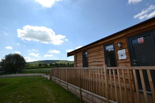 a wooden cabin with a fence in a field at The Chiltern Lodges at Upper Farm Henton in Chinnor