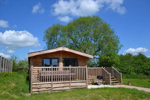 a small wooden cabin with a porch at The Chiltern Lodges at Upper Farm Henton in Chinnor