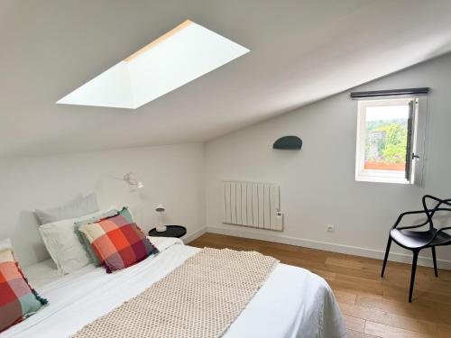 a white bedroom with a bed and a window at Duplex de la Glacière Maison Châteaux & Lavandes in Grignan