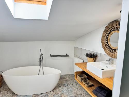 a bathroom with a large white tub and a sink at Duplex de la Glacière Maison Châteaux & Lavandes in Grignan