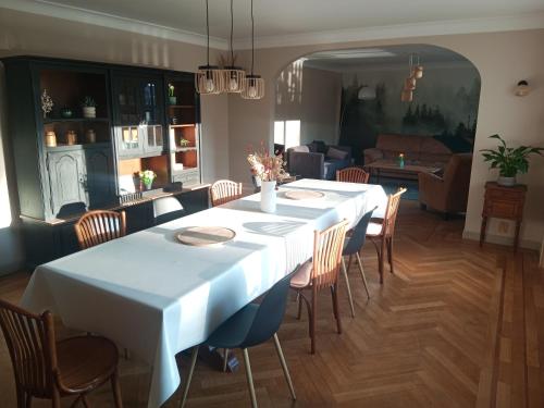 une salle à manger avec une table et des chaises blanches dans l'établissement Gîte Sous le marronnier jusqu'à 10 personnes, à Hadol
