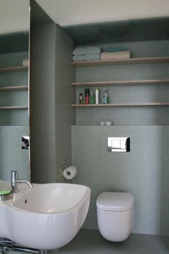 a bathroom with a sink and a toilet and a mirror at Landloft in Sausal