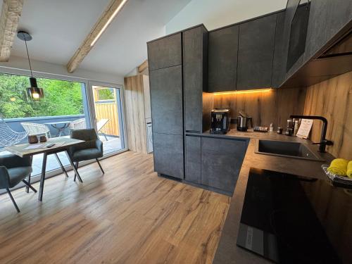 a kitchen with black cabinets and a table with chairs at Das Goldjuwel - Luxury Apartments with private Spa in Goldegg