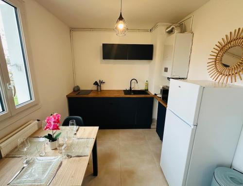 a kitchen with a table and a white refrigerator at Studio Lumineux avec Balcon - Proche Gare & Centre in Montargis