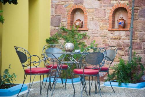 a table and four chairs in front of a stone wall at AnnaDes Apartments & Studios Chios in Karfas