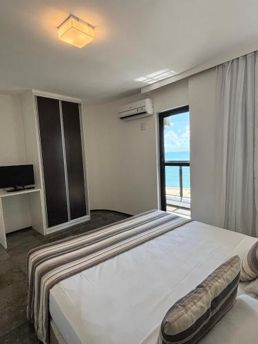 a bedroom with a large bed and a large window at Hotel Brasil Tropical in Fortaleza