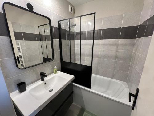 a bathroom with a sink and a mirror and a tub at Jungle Azur in Cogolin