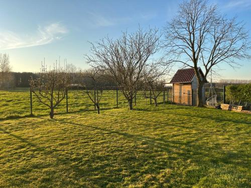 a small building in a field with trees in the foreground at La ferme du paradis in Merris