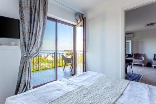 a bedroom with a bed and a view of a balcony at Azur Villa - Panoramic Escape in Balatonalmádi