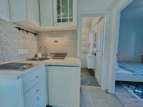 a kitchen with white cabinets and a sink and a bathroom at Azur Villa - Panoramic Escape in Balatonalmádi