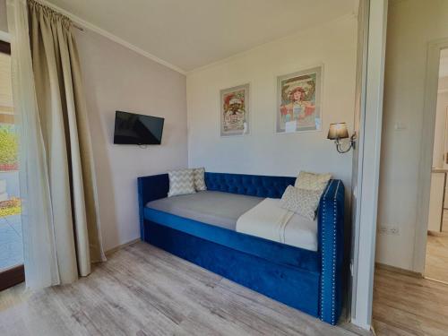 a blue couch in a room with a tv at Azur Villa - Panoramic Escape in Balatonalmádi