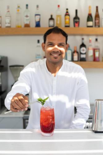 a man in a kitchen stirring a drink with a spoon at Paradise View Hotel in Paradise Beach