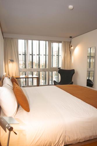 a bedroom with a large white bed with a large window at Opta Coliving Punta Carretas in Montevideo