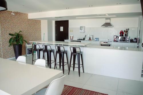 a kitchen with white counter tops and bar stools at Opta Coliving Punta Carretas in Montevideo