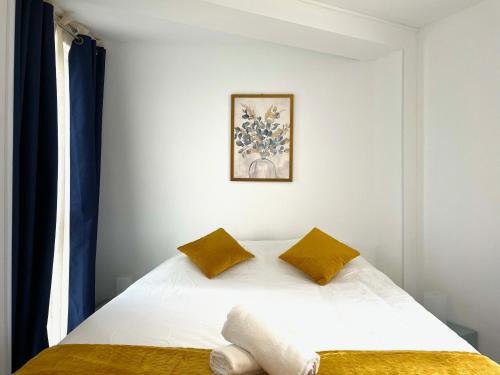 une chambre avec un lit blanc avec des oreillers jaunes dans l'établissement Agréable 2 chambres avec Parking Proche Orly et T12, à Morangis