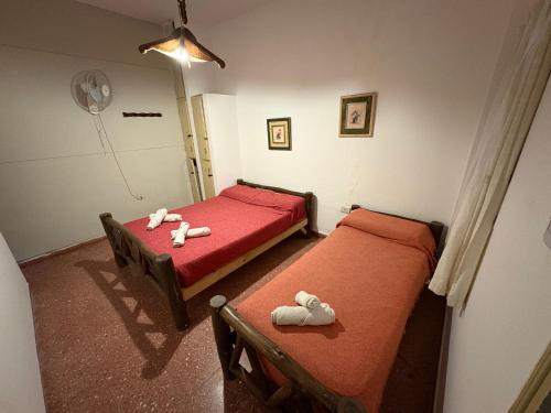 two beds in a room with red sheets and stuffed animals at Jujuy Hostel in San Salvador de Jujuy