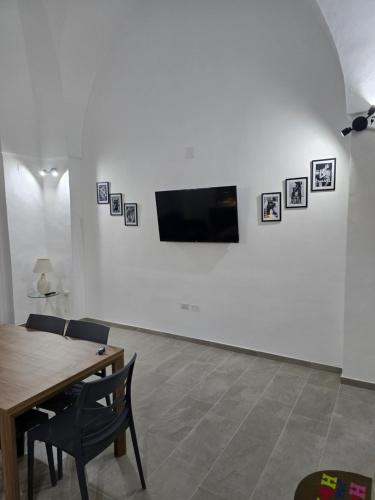 a living room with a table and a tv on a wall at Casa Vacanza S Elia in Veglie