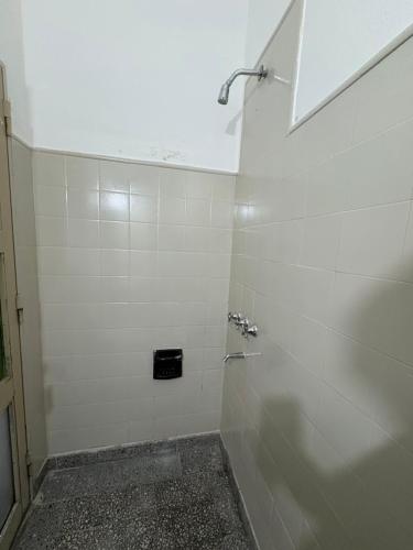 a white tiled bathroom with a shower with a shower at Jujuy Hostel in San Salvador de Jujuy