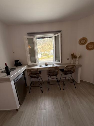 a kitchen with three chairs and a table and a window at Chrysa House in Kamarai