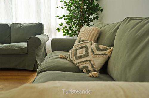 a green couch with a throw pillow on it at Apartamento Corimar - Céntrico y accesible para personas con movilidad reducida in San Vicente de la Barquera