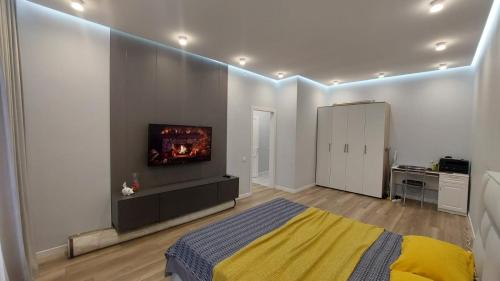 アスタナにある1-комнатная люкс квартира в районе Ханшатырのベッドと壁にテレビが掛かった寝室