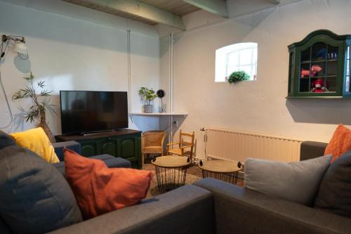 a living room with couches and a flat screen tv at Bed & breakfast De Loeghoeve in Anderen
