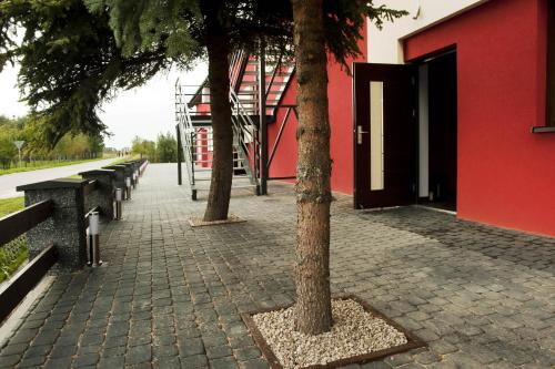 a red building with trees and benches in front of it at Zajazd CISZA in Ciągowice