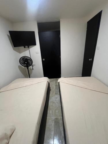 a room with two beds and a black door at Hostal Jireth in Floridablanca