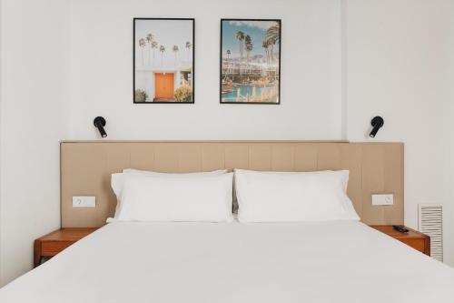 a bedroom with a white bed with three pictures on the wall at White Beach Apartment in Valencia