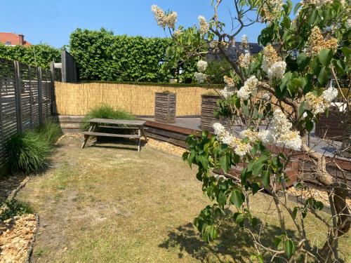 a wooden bench in a garden with a fence at Studio Bella in De Panne