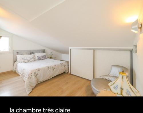Un dormitorio blanco con una cama y una silla. en Appartements Au Cros De Cagnes, en Cros-de-Cagnes