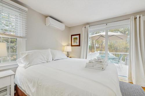 une chambre avec un lit et un balcon avec un parasol dans l'établissement Cozy Charming Cottage, à Brewster