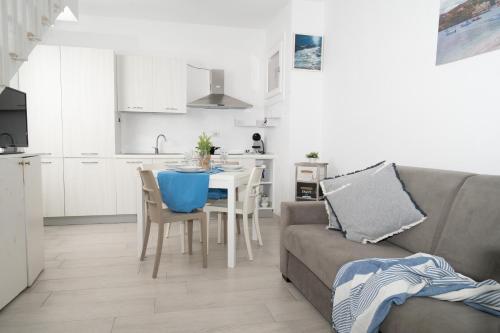 a kitchen and a living room with a couch and a table at White, Villetta with pool in Viddalba