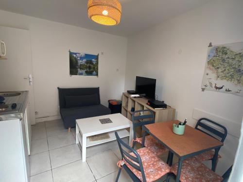 Elle comprend un petit salon avec une table et un bureau. dans l'établissement La petite amiénoise au calme, stationnement gratuit, à Amiens