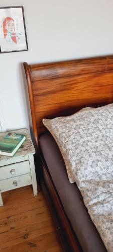 a bed with a wooden headboard next to a night stand at Scandinavian city apartment in Aarhus