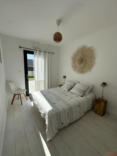 une chambre blanche avec un lit et une chaise dans l'établissement Ker Nany, à Sainte-Marine